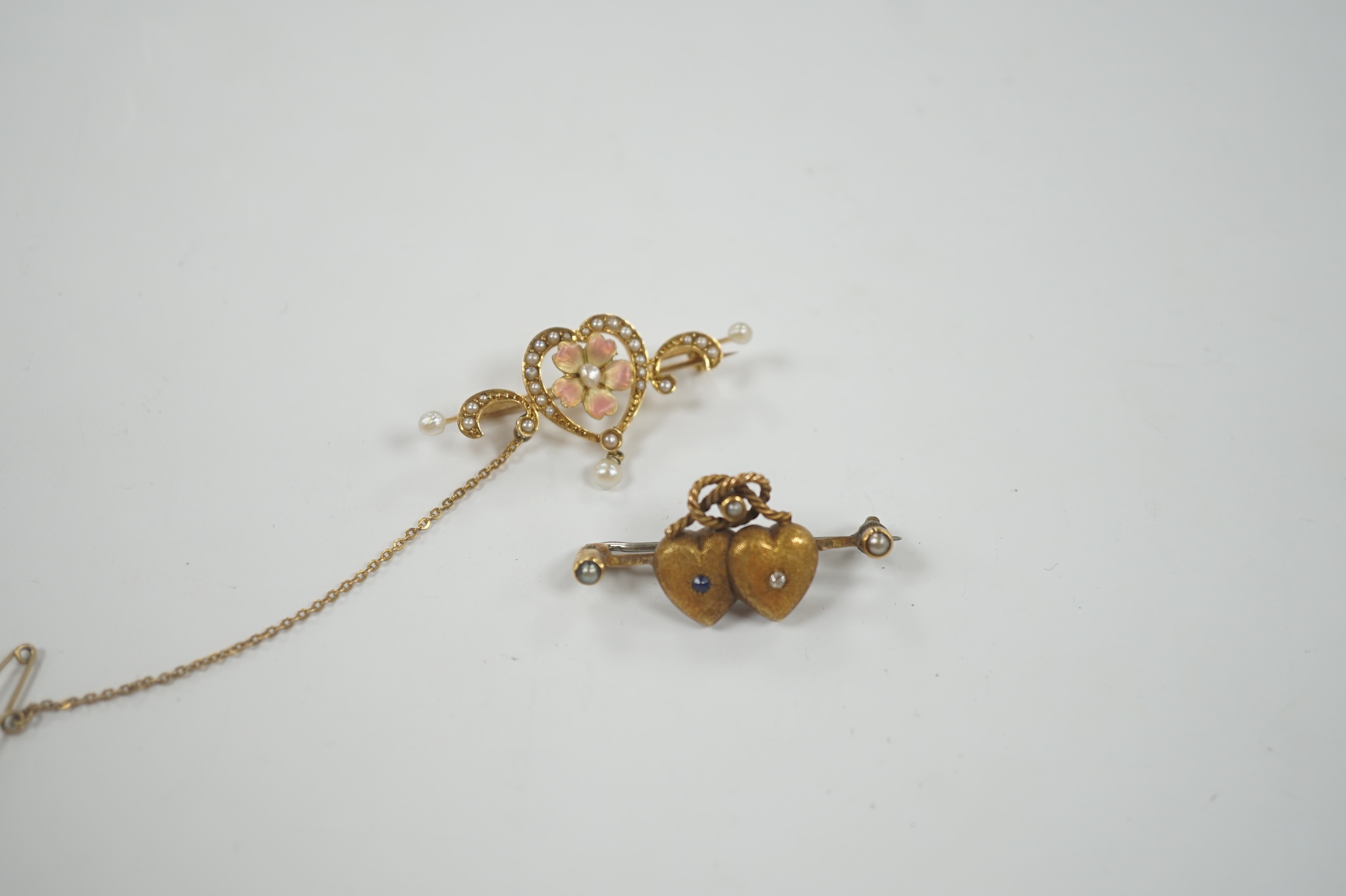 An Edwardian 625 yellow metal, enamel and seed pearl set drop bar brooch, with central heart shaped motif, 40mm, together with a yellow metal and gem set twin hearts bar brooch.